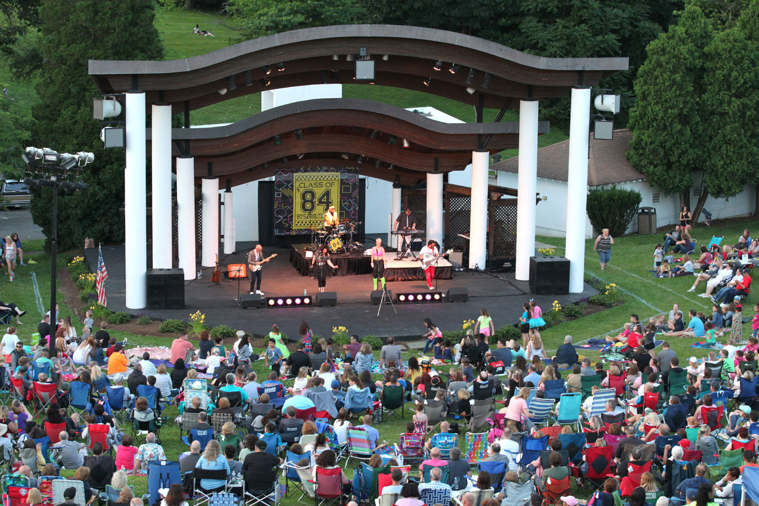 crowd sitting in chairs near band performing center stage