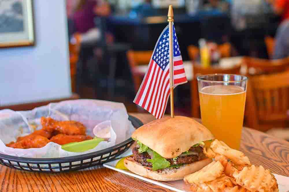 burger wings juice and fries on table