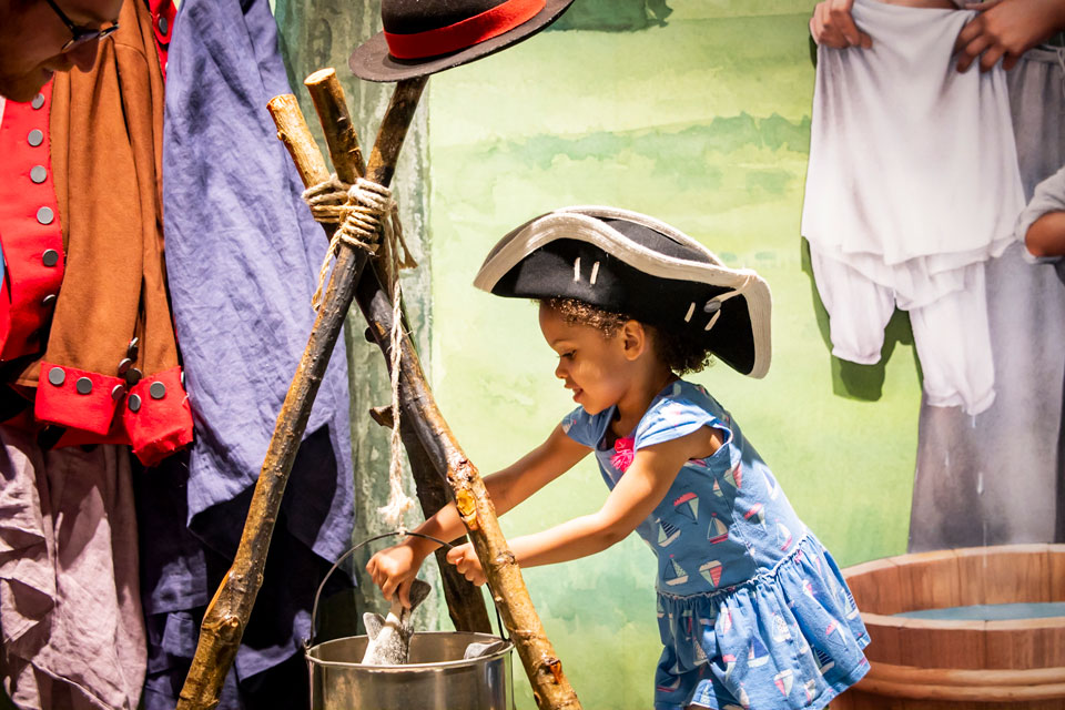 little girl picking up a fish from bucket