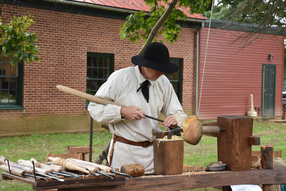 a person carving wood on a wooden lathe machine