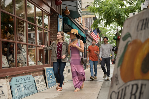 people walking on side walk passing by stores