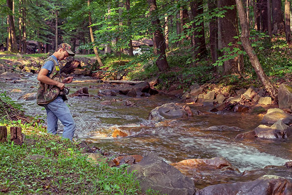 person fishing standing on the bank of Creek