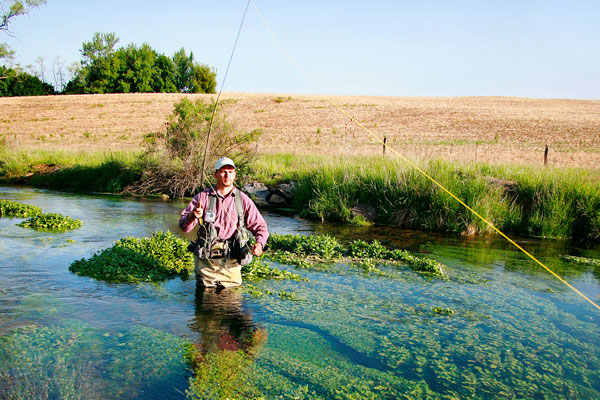 a person fishing standing in river creek