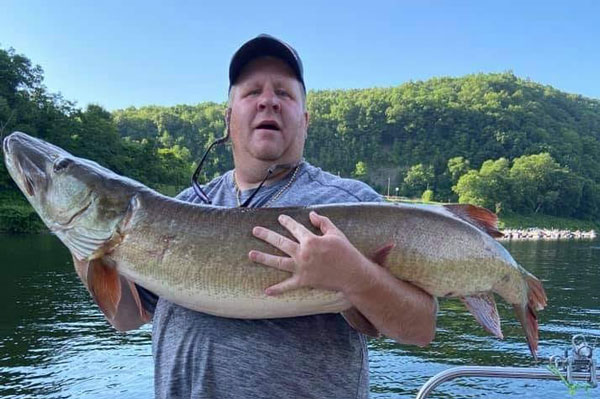 a guy holding a huge fish caught standing on dOck