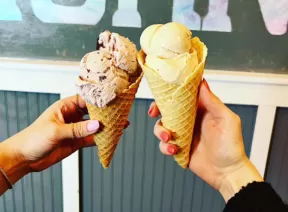 two persons holding icecream in hands