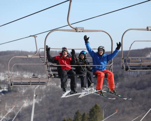 three people riding on high chair