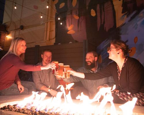 people enjoying beer near fire pit