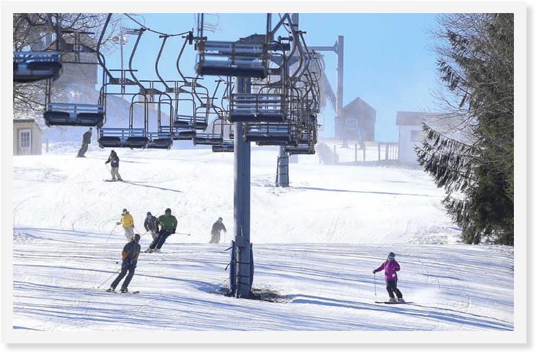 Skiiers descending a slope underneath a ski lift